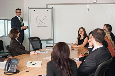 Photo of individuals in a board room listening to a presentation
