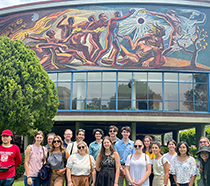 Schar School students, along with Professor Guadalupe Correa-Cabrera (far right), stand in front of one of the many murals at the National Autónomous University of México, the largest university in Latin America.