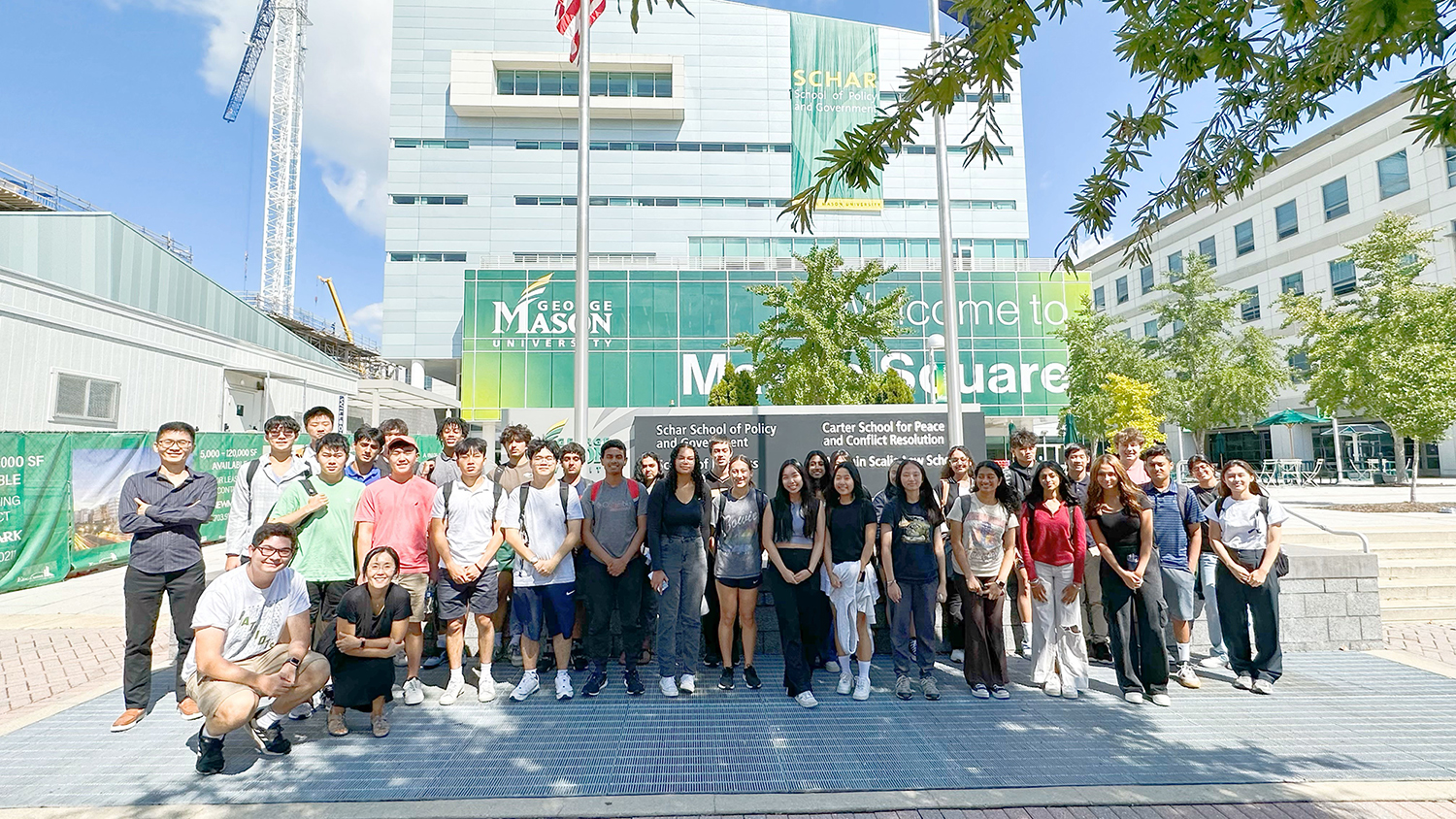 A group of high school and college students from the summer 2023 internship standing in front of Van Metre Hall on Mason Square.