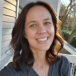 A woman with long hair stands outside on a porch