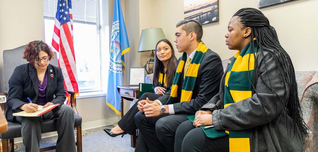 Three students sitting in a lawmaker's office with a staffer