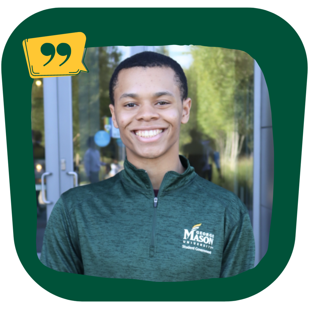 Scott Tatum smiles while wearing a dark green george mason quarterzip shirt