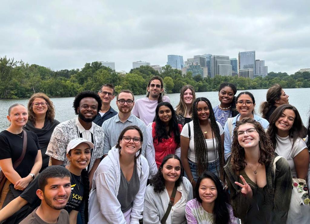 A group of students stand in front of a river and smile