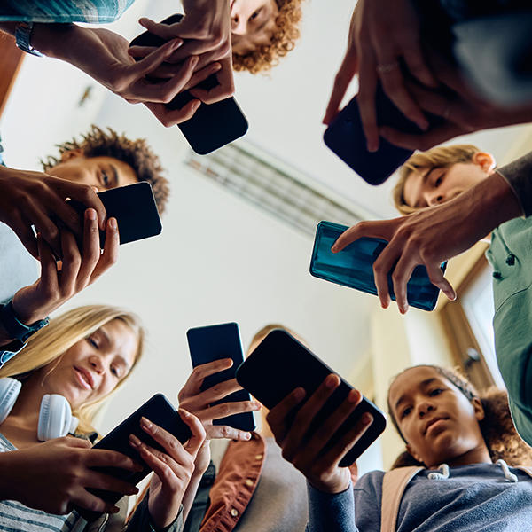 A group of students stand in a circle while using their cell phones