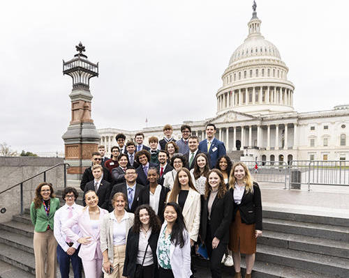 A group of students stand on the steps in front of the U.S. Capitol