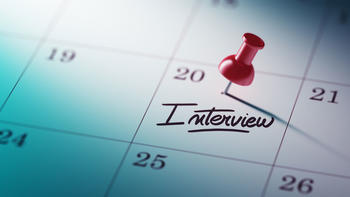 A calendar with a pin in a date and the word Interview written below it