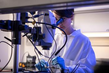 A woman in a lab coat using a microscope