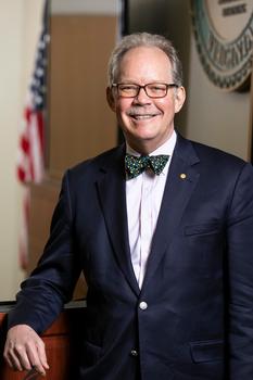 A man in a blue suit and bow tie smiles at the camera.