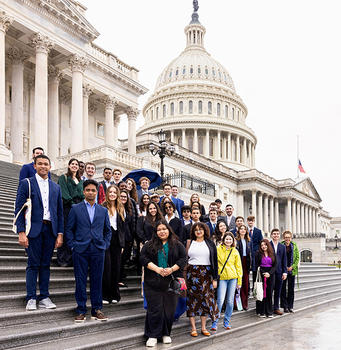A group of people stand on the steps in front of the Capitol Building.